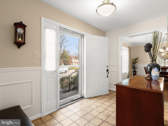 entryway with light tile patterned flooring and a wainscoted wall