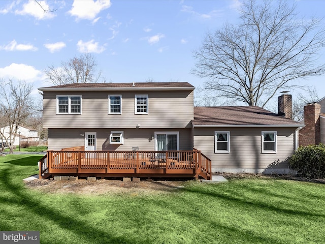 rear view of property featuring a wooden deck, a lawn, and a chimney