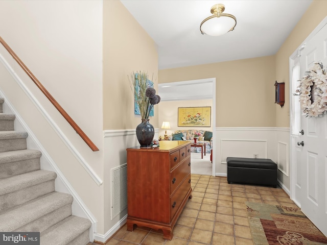 entryway featuring stairway, wainscoting, and visible vents