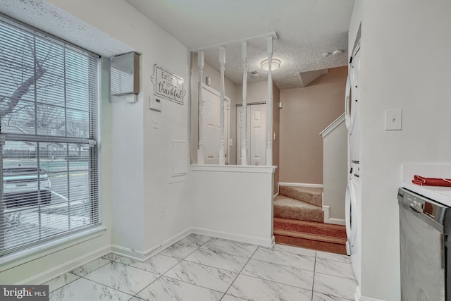 interior space with marble finish floor, a textured ceiling, baseboards, and stairs