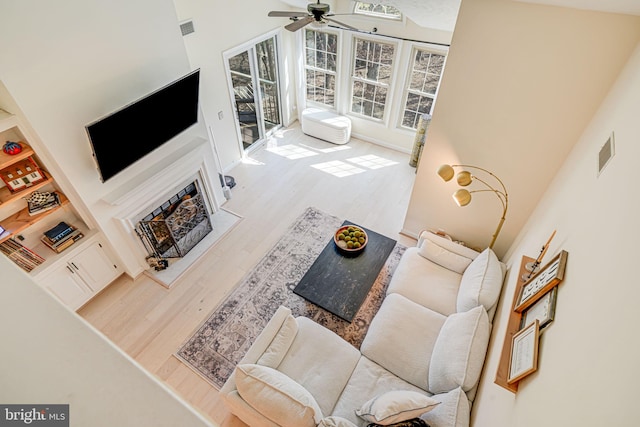 living room with visible vents, a fireplace, wood finished floors, and a ceiling fan