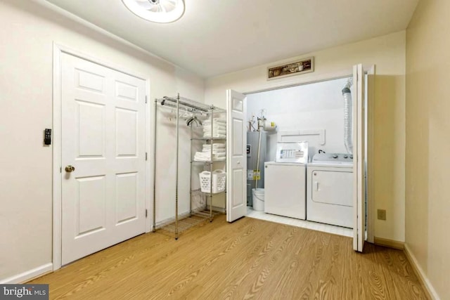 laundry room featuring washer and clothes dryer, water heater, light wood-style flooring, laundry area, and baseboards