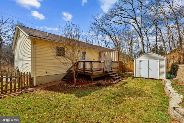 rear view of house featuring an outbuilding, a yard, a storage shed, fence, and a deck