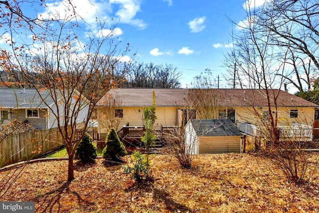 rear view of house with a storage shed, fence, a deck, and an outdoor structure