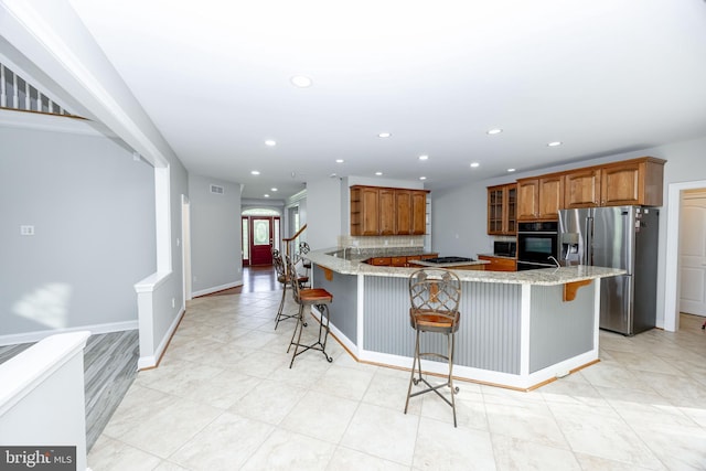 2729 Hollow View Dr, Finksburg, MD 21048 - kitchen featuring stainless steel refrigerator with ice dispenser, a breakfast bar area, a peninsula, brown cabinetry, and recessed lighting