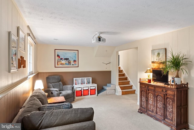 living room with stairway, a textured ceiling, and carpet flooring