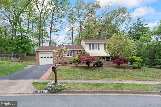 split level home with a garage, driveway, a front yard, and brick siding