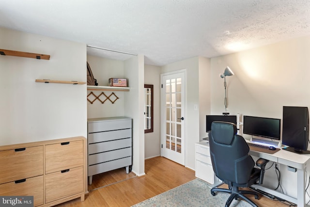 office featuring baseboards, french doors, light wood-style floors, and a textured ceiling