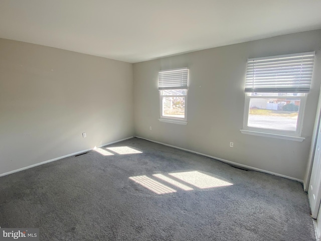 carpeted spare room featuring visible vents and baseboards