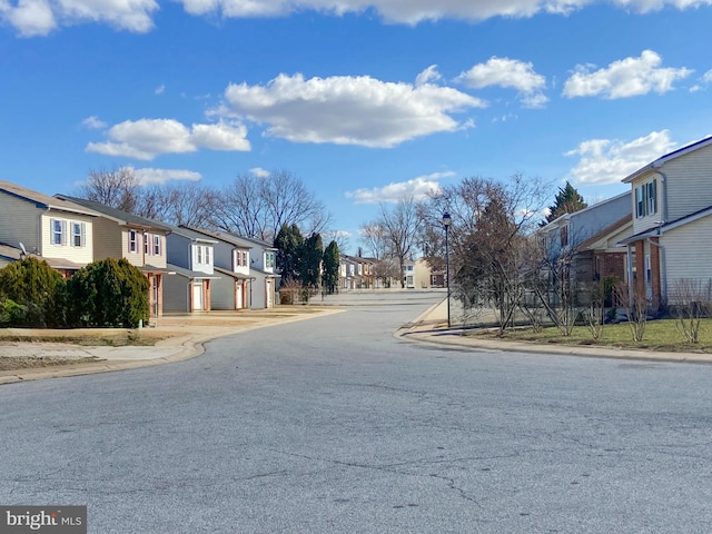 view of road featuring sidewalks, a residential view, curbs, and street lights