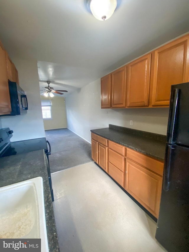 kitchen with a sink, a ceiling fan, brown cabinets, black appliances, and dark countertops