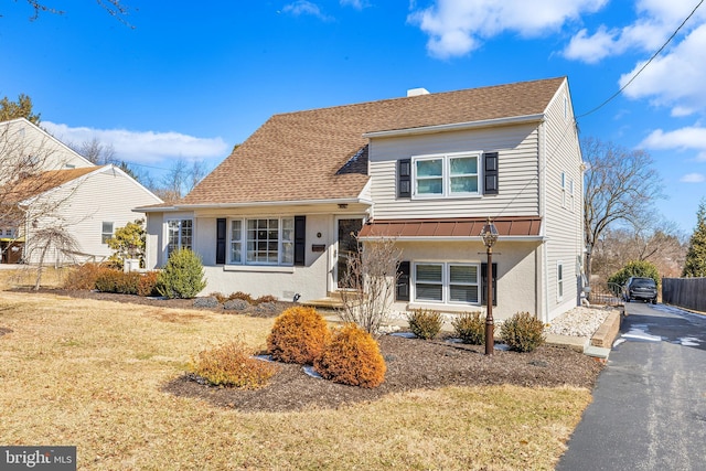 tri-level home with aphalt driveway, fence, roof with shingles, stucco siding, and a front yard