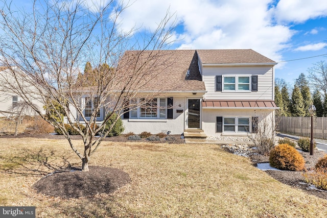 view of front of home with entry steps, fence, roof with shingles, stucco siding, and a front yard