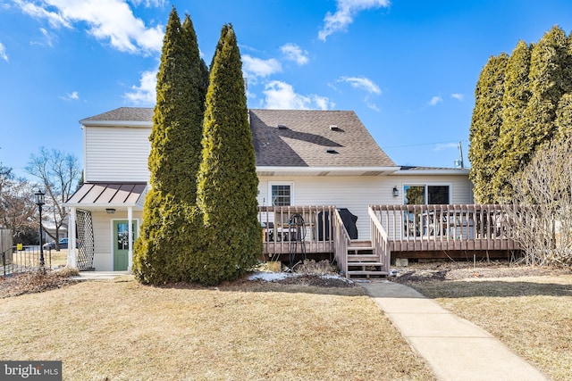 back of property featuring a shingled roof, a lawn, metal roof, a standing seam roof, and a wooden deck