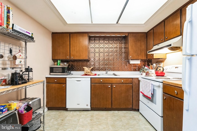 kitchen featuring under cabinet range hood, white appliances, a sink, light countertops, and brown cabinetry