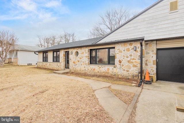 ranch-style house with stone siding, concrete driveway, a shingled roof, and a garage