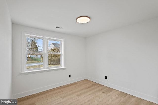 empty room with visible vents, light wood-style floors, and baseboards