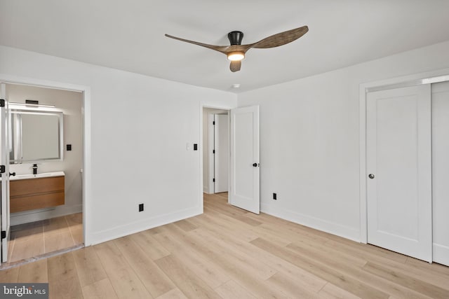 unfurnished bedroom with light wood-type flooring, baseboards, and connected bathroom