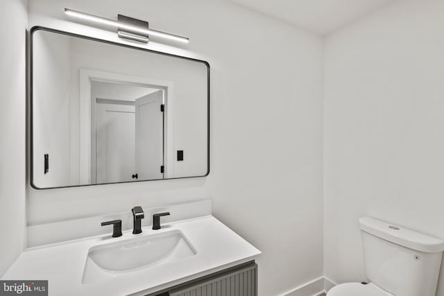 bathroom with baseboards, toilet, and vanity