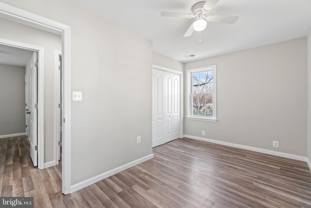 unfurnished bedroom featuring a closet, visible vents, baseboards, and wood finished floors