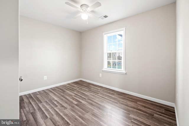 empty room with a ceiling fan, dark wood finished floors, visible vents, and baseboards