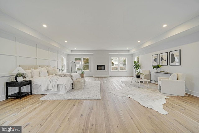 bedroom with light wood-type flooring, baseboards, a decorative wall, and recessed lighting