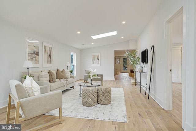 living area with light wood-type flooring, vaulted ceiling with skylight, baseboards, and recessed lighting