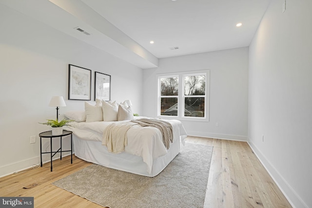 bedroom with light wood finished floors, visible vents, and baseboards