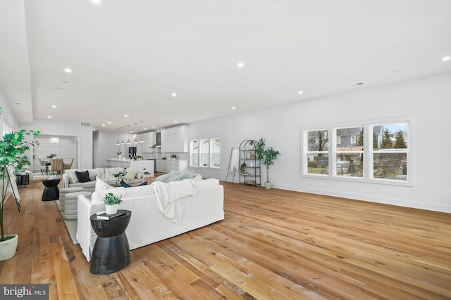 living area with light wood-style flooring, visible vents, baseboards, and recessed lighting