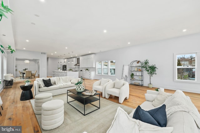 living area with light wood-type flooring, baseboards, visible vents, and recessed lighting