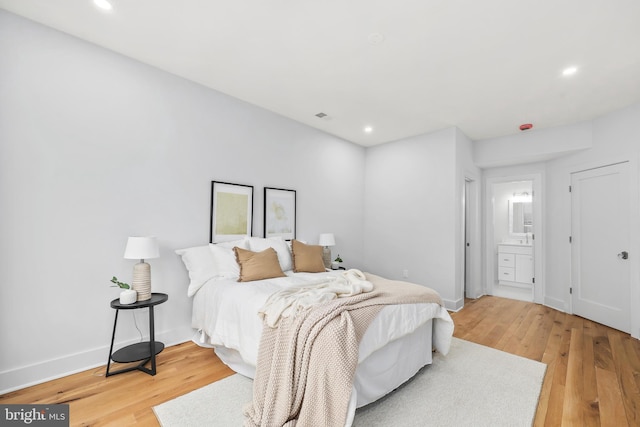 bedroom with ensuite bathroom, recessed lighting, visible vents, baseboards, and light wood finished floors