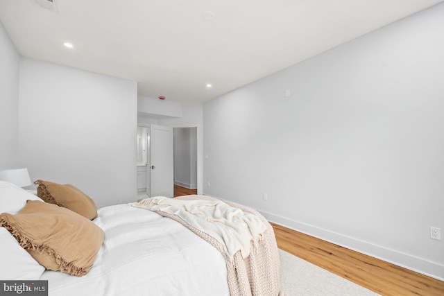 bedroom featuring baseboards, wood finished floors, and recessed lighting