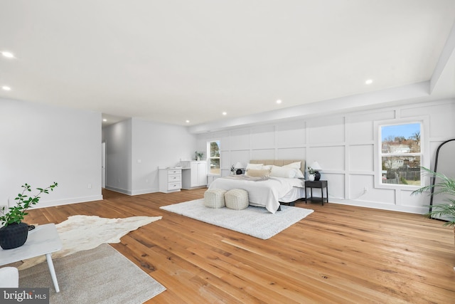 bedroom with baseboards, recessed lighting, light wood-type flooring, and a decorative wall