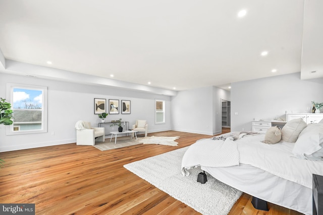 bedroom with baseboards, light wood finished floors, multiple windows, and recessed lighting