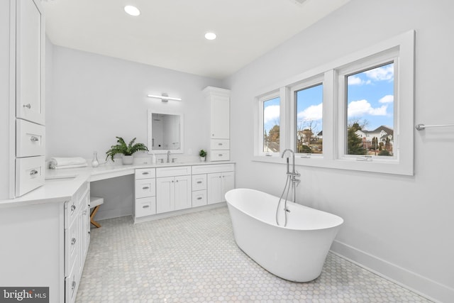 full bathroom featuring recessed lighting, a soaking tub, vanity, and baseboards