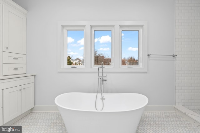 bathroom featuring a soaking tub, plenty of natural light, and baseboards