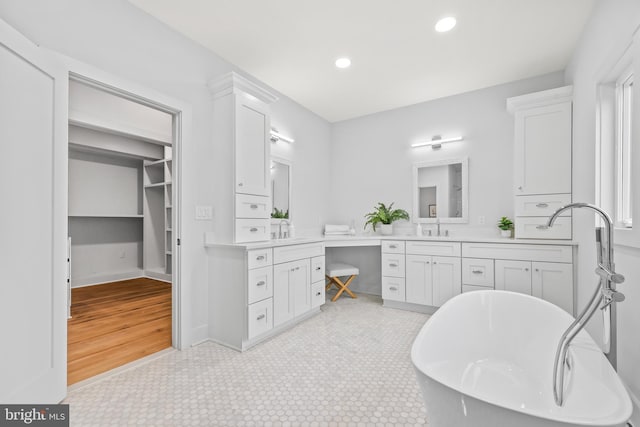 bathroom with a freestanding tub, vanity, and recessed lighting