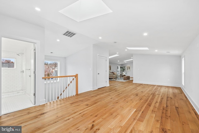 unfurnished living room featuring light wood-style floors, visible vents, lofted ceiling with skylight, and recessed lighting