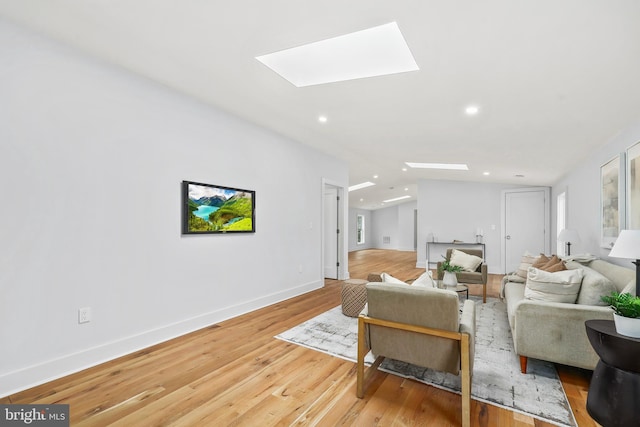 living room with light wood-style floors, recessed lighting, lofted ceiling with skylight, and baseboards