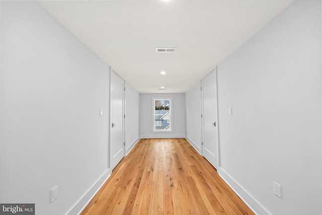 corridor with baseboards, visible vents, and light wood-style floors