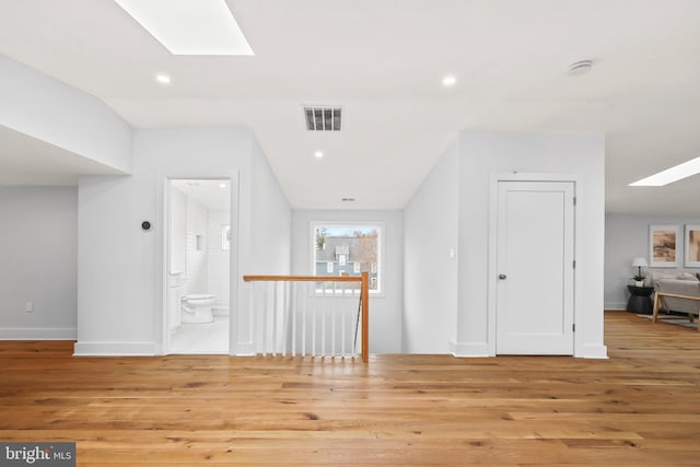 interior space featuring a skylight, recessed lighting, visible vents, wood finished floors, and baseboards