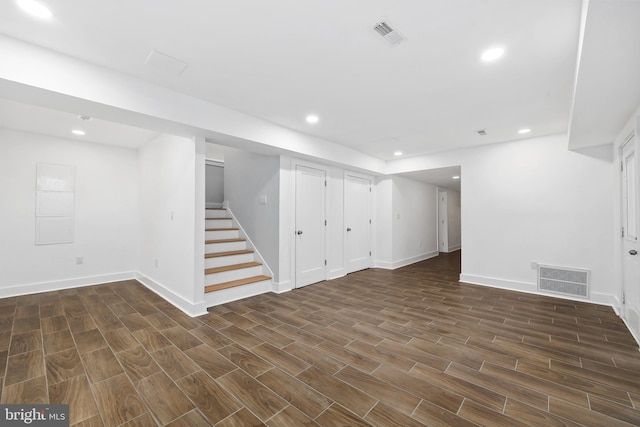 finished basement featuring stairway, recessed lighting, visible vents, and wood finish floors