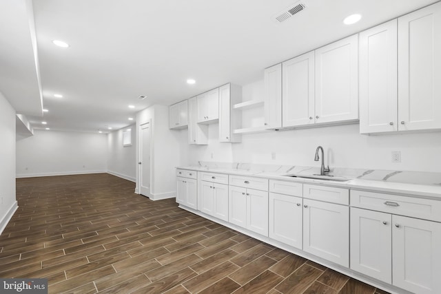 kitchen with wood tiled floor, white cabinetry, a sink, and recessed lighting