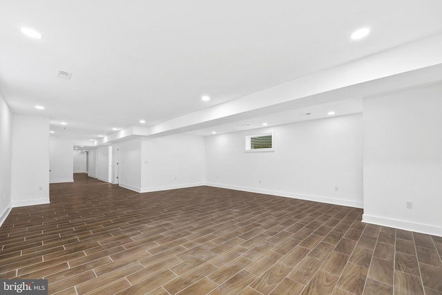 finished below grade area featuring wood tiled floor, visible vents, baseboards, and recessed lighting