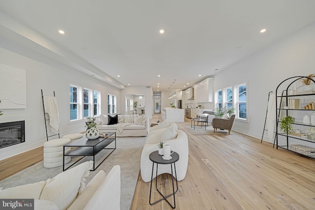 living room featuring light wood finished floors, recessed lighting, and a glass covered fireplace