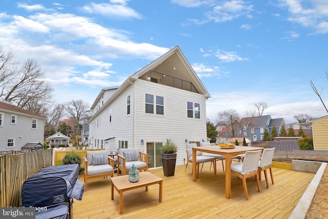 rear view of property featuring fence, outdoor dining area, and a wooden deck