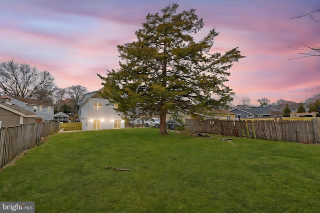 yard at dusk featuring a fenced backyard