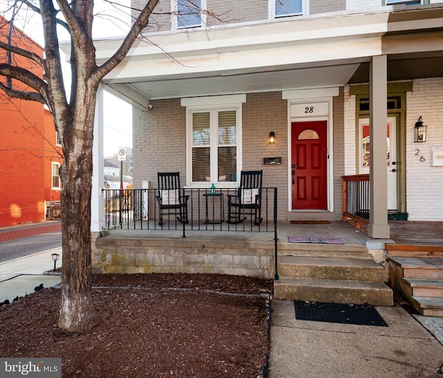 view of exterior entry with covered porch and brick siding