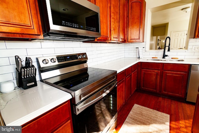 kitchen with dark wood-style floors, stainless steel appliances, light countertops, a sink, and dark brown cabinets