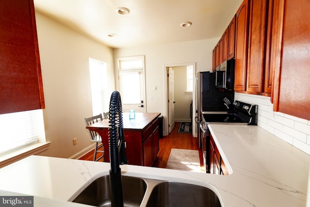 kitchen featuring range with electric cooktop, wood finished floors, backsplash, light stone countertops, and stainless steel microwave